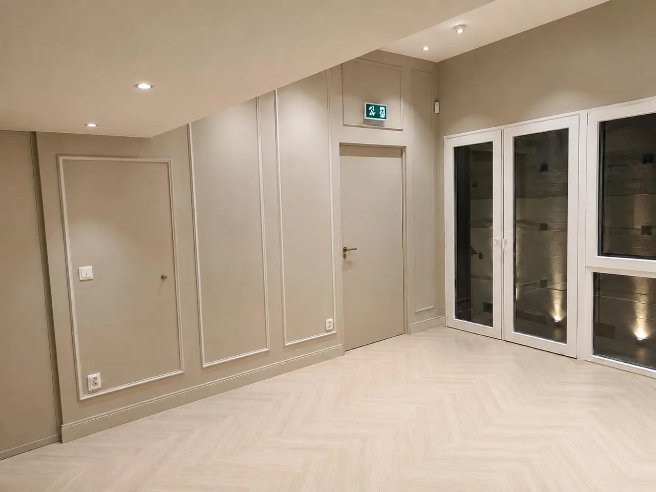 Ruimte met wandpanelen, visgraatvloer en glazen deuren